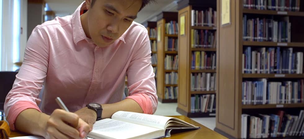 Young man at Asia campus studies in library.