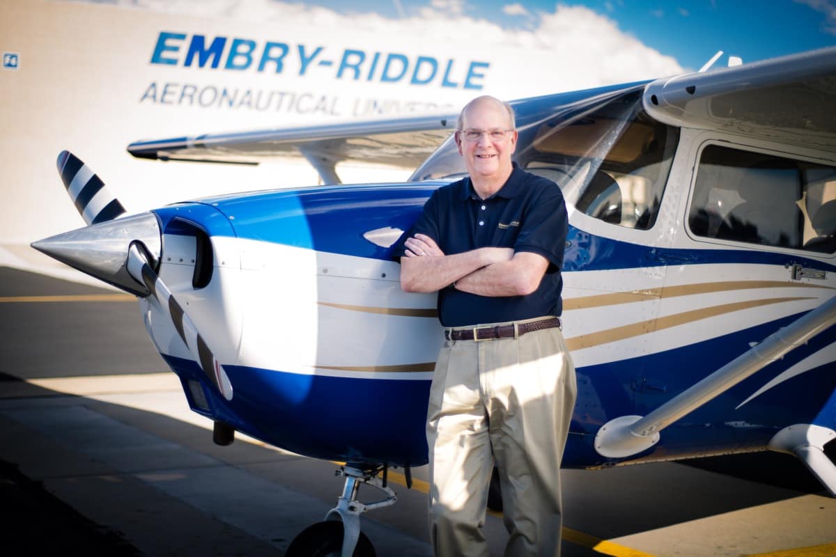 Chancellor Dr. Frank Ayers stands in front of one of Embry-Riddle Prescott Campus' planes
