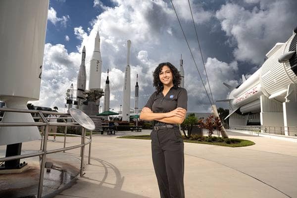 Aviation Week 20 Twenties honoree Liz Bosch stands between a Delta II (left) and a Saturn 1B in the Rocket Garden at Kennedy Space Center