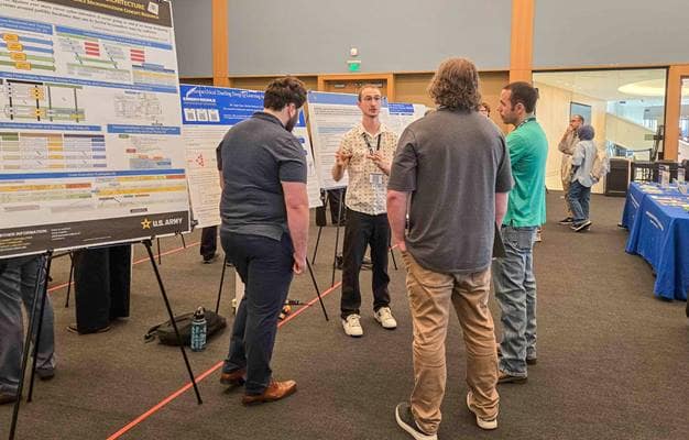 At Embry-Riddle's Cyber Rodeo, Electrical Engineering and Computer Science student Logan Luna (center) presents research on a cybersecurity defense system that autonomously adapts to new threats. To his left is fellow Electrical Engineering and Computer Science student Matt Berkowitz, who also worked on the project.