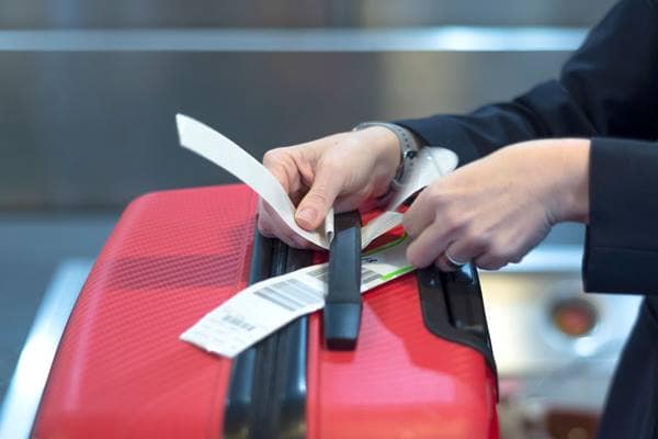 Airline working adding a tag to a luggage handle