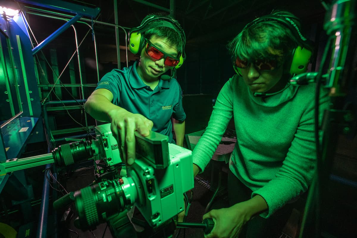 Dr. Zheng Zhang (left) works with Ph.D. candidate Dhuree Seth to prepare high-speed cameras inside Embry-Riddle’s wind tunnel, as part of an effort to study the airwake of a model U.S. Navy frigate. 