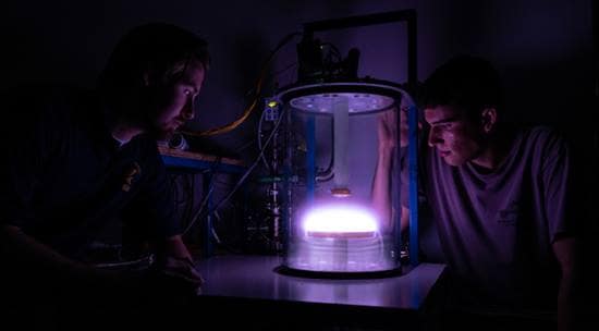 Engineering Physics graduate student Liam Gunter and Aerospace Engineering undergraduate Kyle Hrenyo peer into a newly commissioned glow-discharge plasma chamber in the Space and Atmospheric Instrumentation Lab. (Photo: Embry-Riddle/Daryl LaBello)