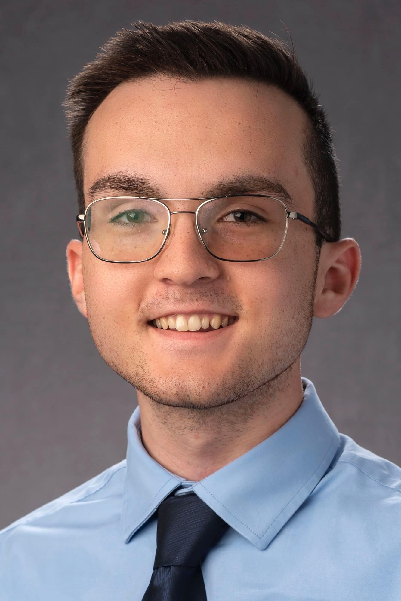 Picture of William McNeil in glasses with blue shirt and black tie