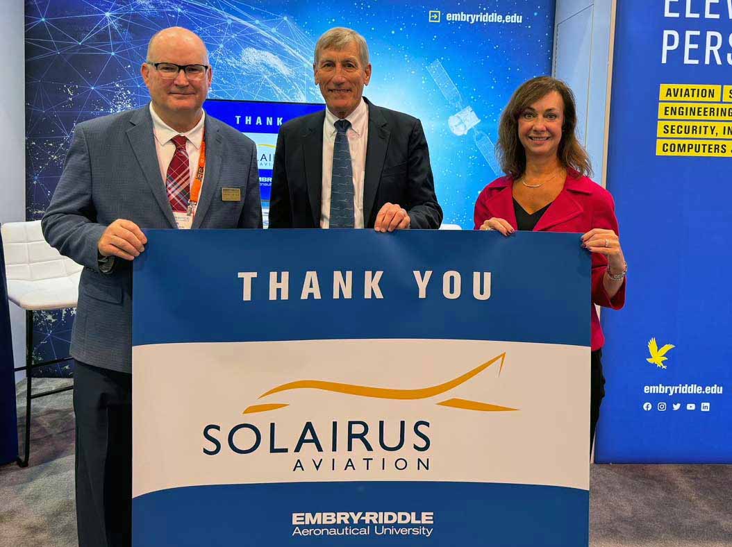Deans Alan Stolzer and Shanan Gibson hold thank you sign with Solairus CEO Dan Drohan
