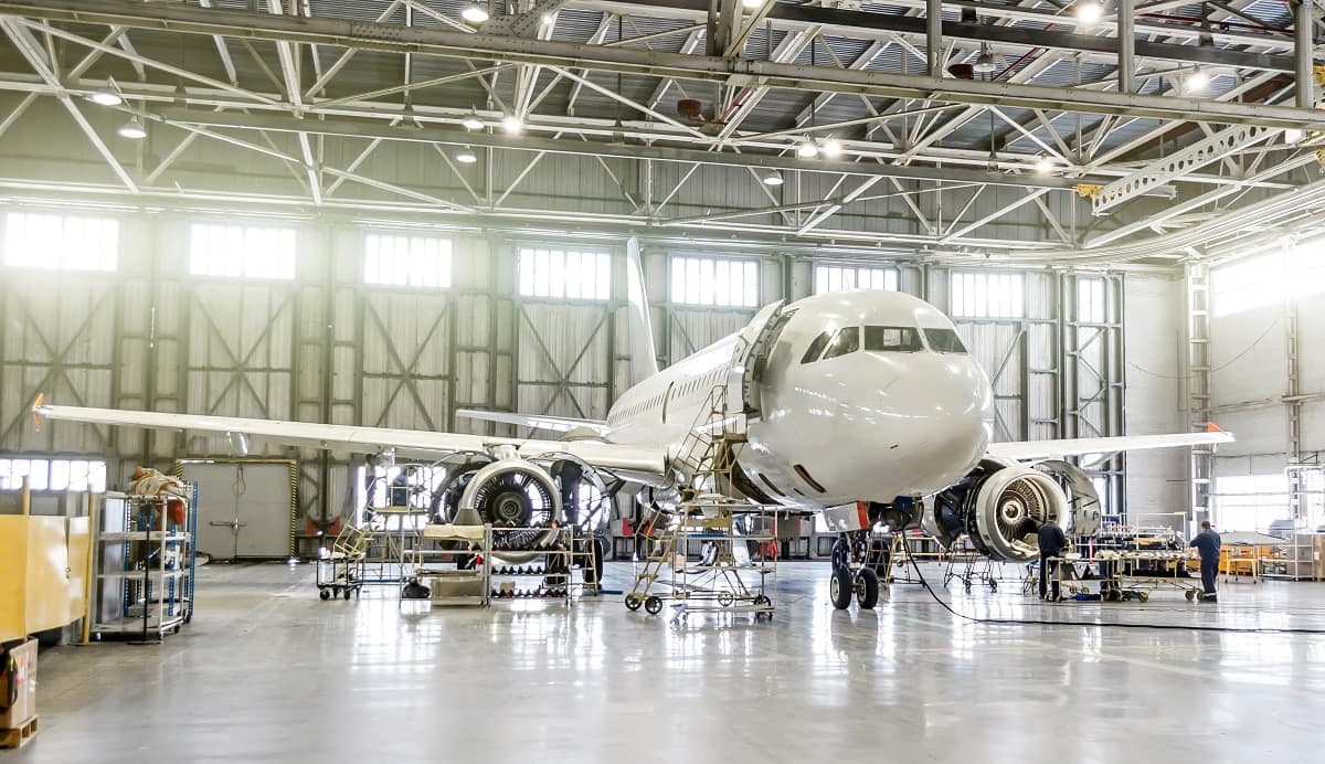 Commercial airliner is worked on in a hangar by aviation maintenance technicians.