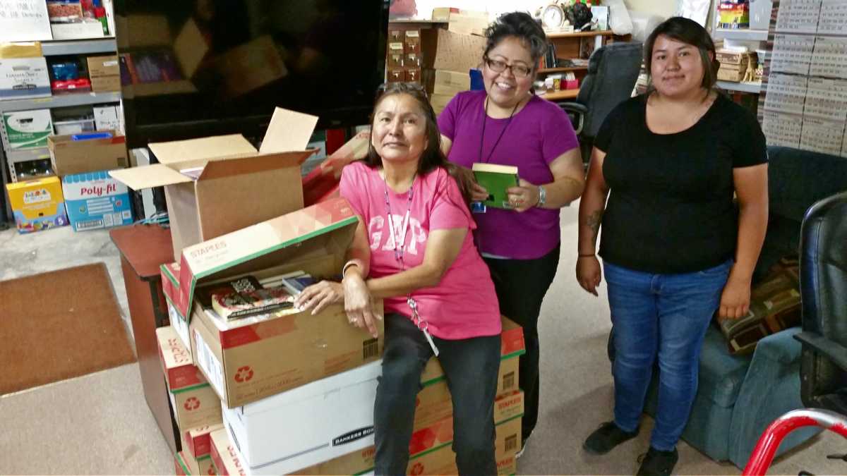 Librarians for the Tuba City Library in Arizona open boxes of books donated by Embry-Riddle Aeronautical University's Prescott campus Phi Kappa Phi chapter