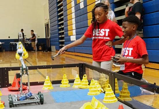 Students from Tuskeegee Public School practice operating their remote-controlled robot. In this portion of the competition, the robot must be able to lift and place small plastic pylons in various locations. (Photo by Alan Marcos Pinto Cesar.)