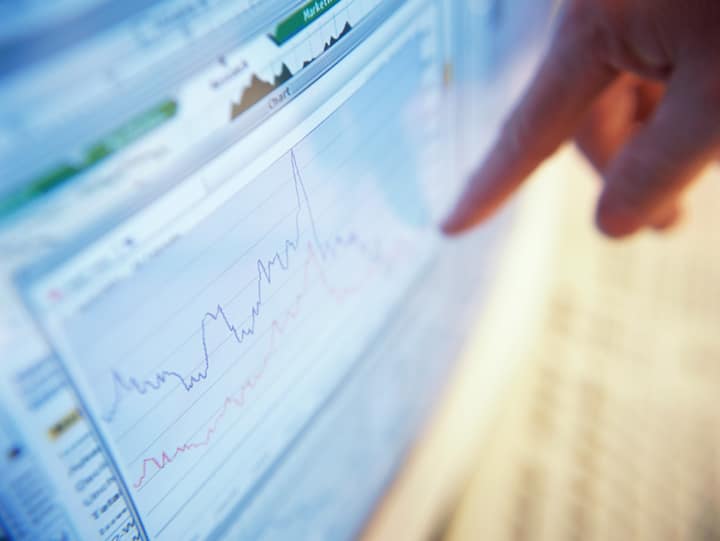 Person pointing to charts on a computer screen