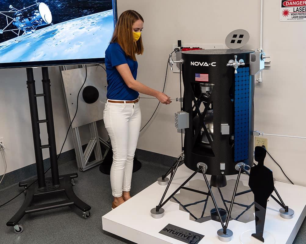 Female student standing with NOVA-C lander model in an ERAU lab.