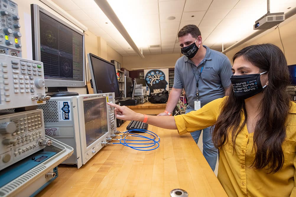 Alumnus and Qorvo engineer Dustin Heil shows ERAU student Sabrina Yepez how to use an RF measuring device.