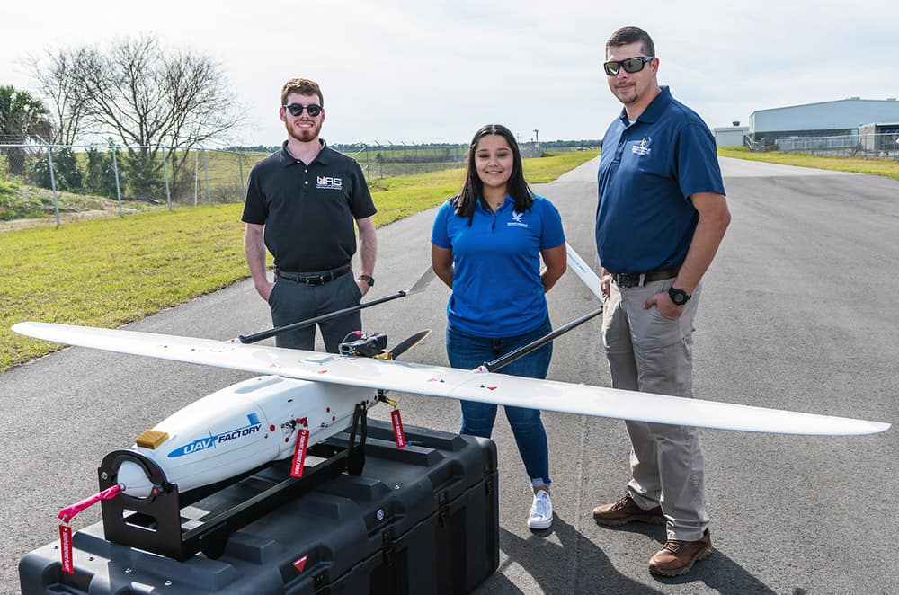 Three Embry-Riddle students and faculty with a Penguin UAS