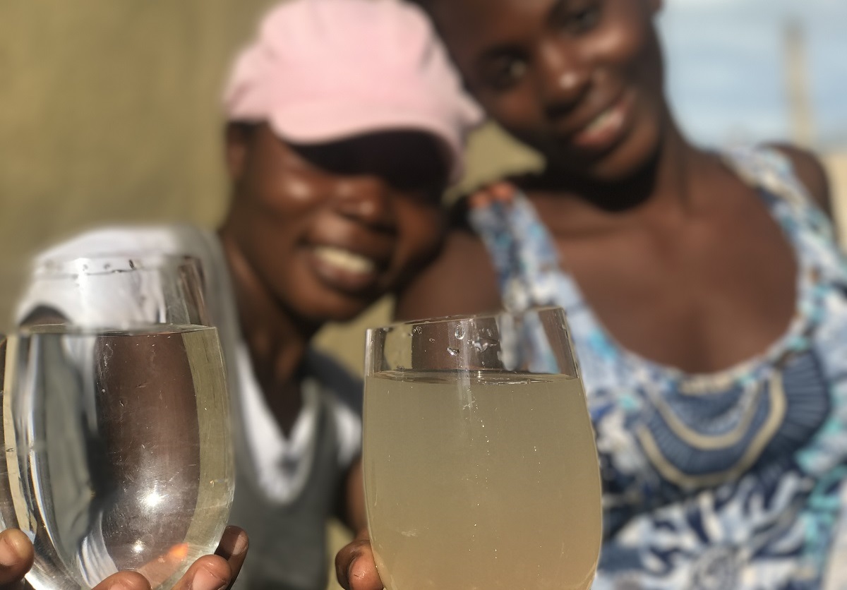 Haitian women hold glasses of purified and unpurified water