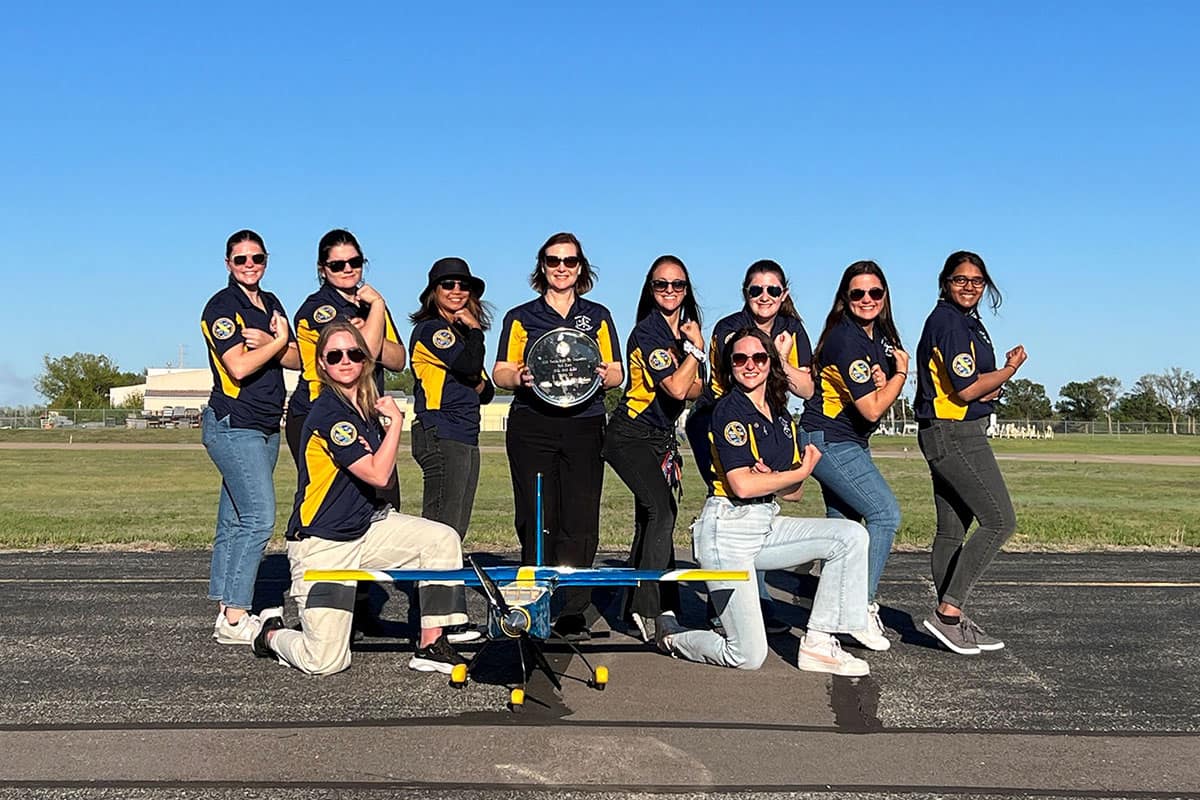The Design/Build/Fly Competition team’s women pose with advisor Kimberly Heinzer, who is holding the team’s award (back row, fourth from left)