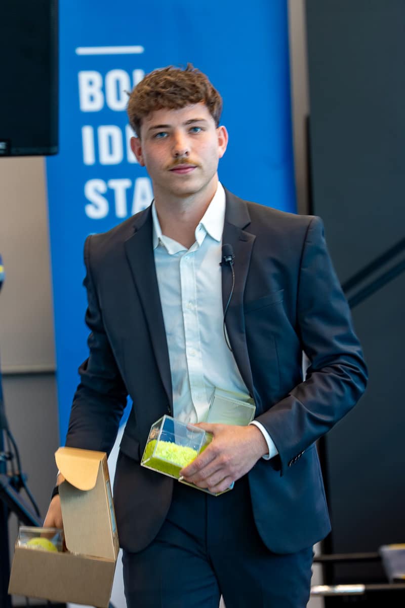 Man in suit holds containers with yellow plastic balls