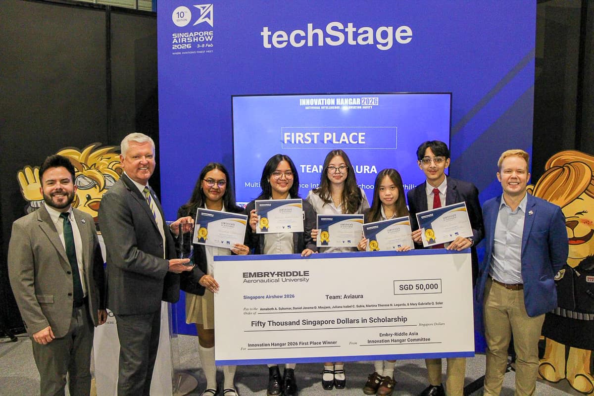 A line of students holding a giant check