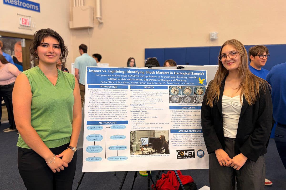 Two female students in front of poster