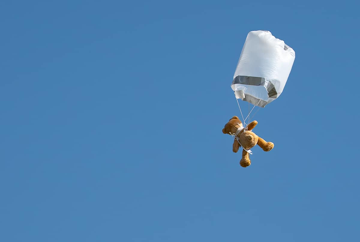 A bear floats down with a plastic parachute