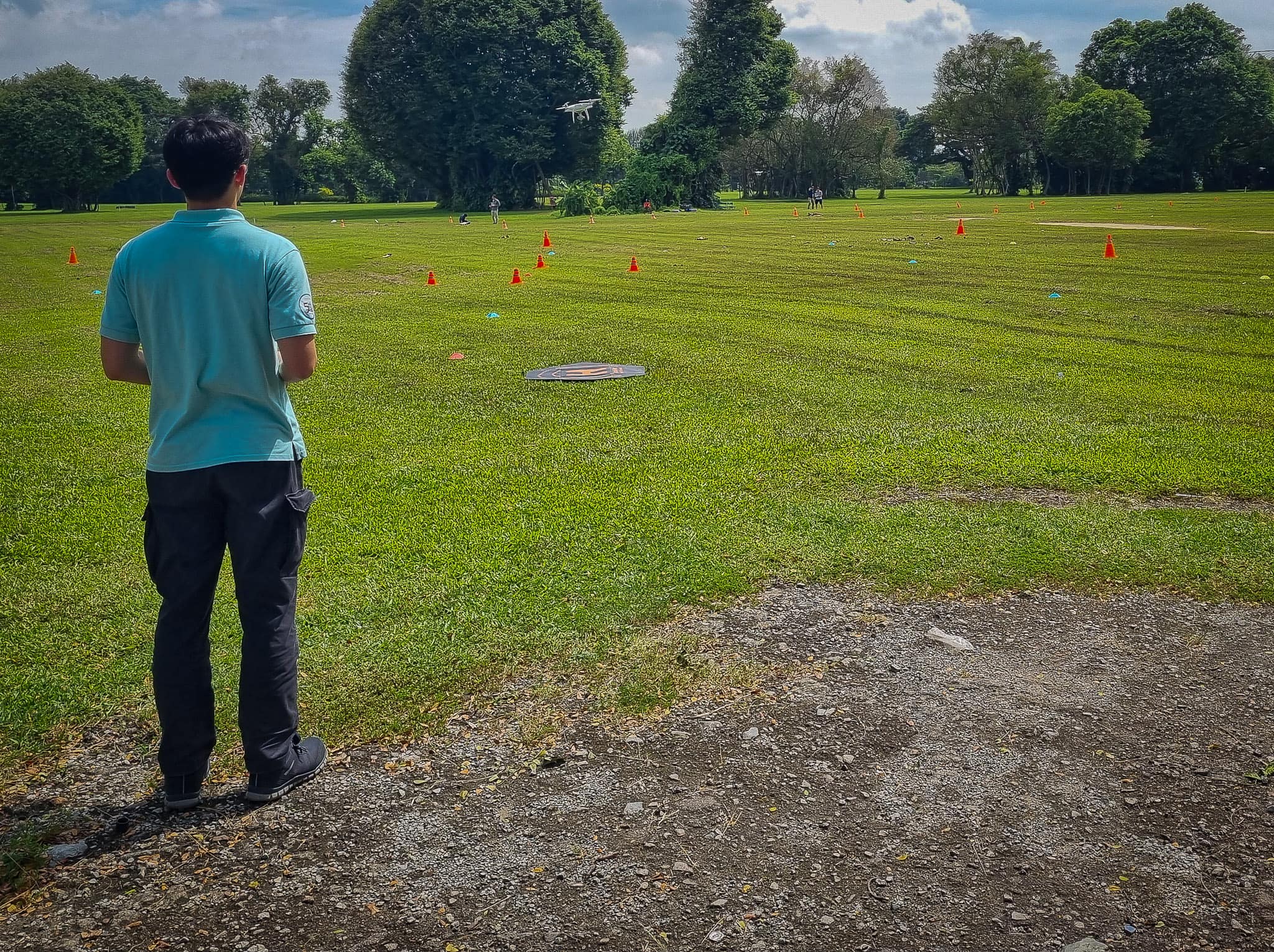 A person standing in a field, flying a drone.