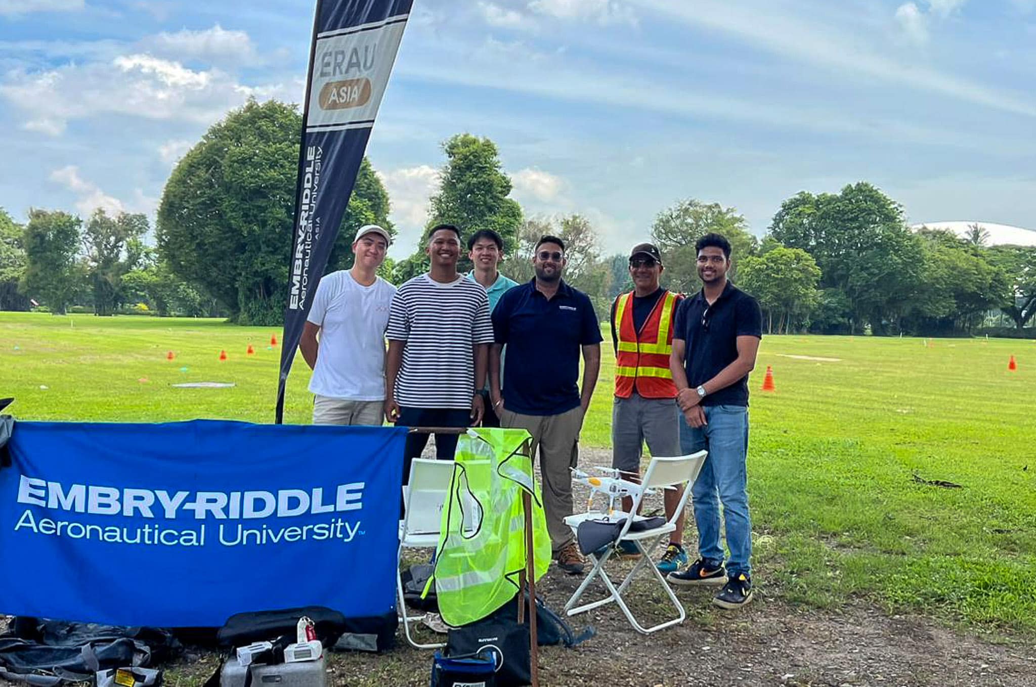 A group of people standing together in front of a drone and a sign which says "Embry-Riddle Aeronautical University".