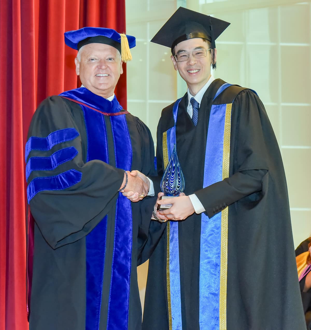 Worldwide Campus Chancellor Dr. John R. Watret shakes hands with Jonathan Hung, the executive director of the Office for Space Technology & Industry at Singapore's National Space Office. An Embry-Riddle alumnus, Hung gave the keynote address at the Dec. 6 commencement for the Asia Campus.
