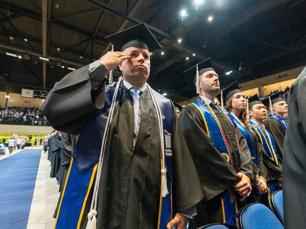 Graduates stand at ceremony