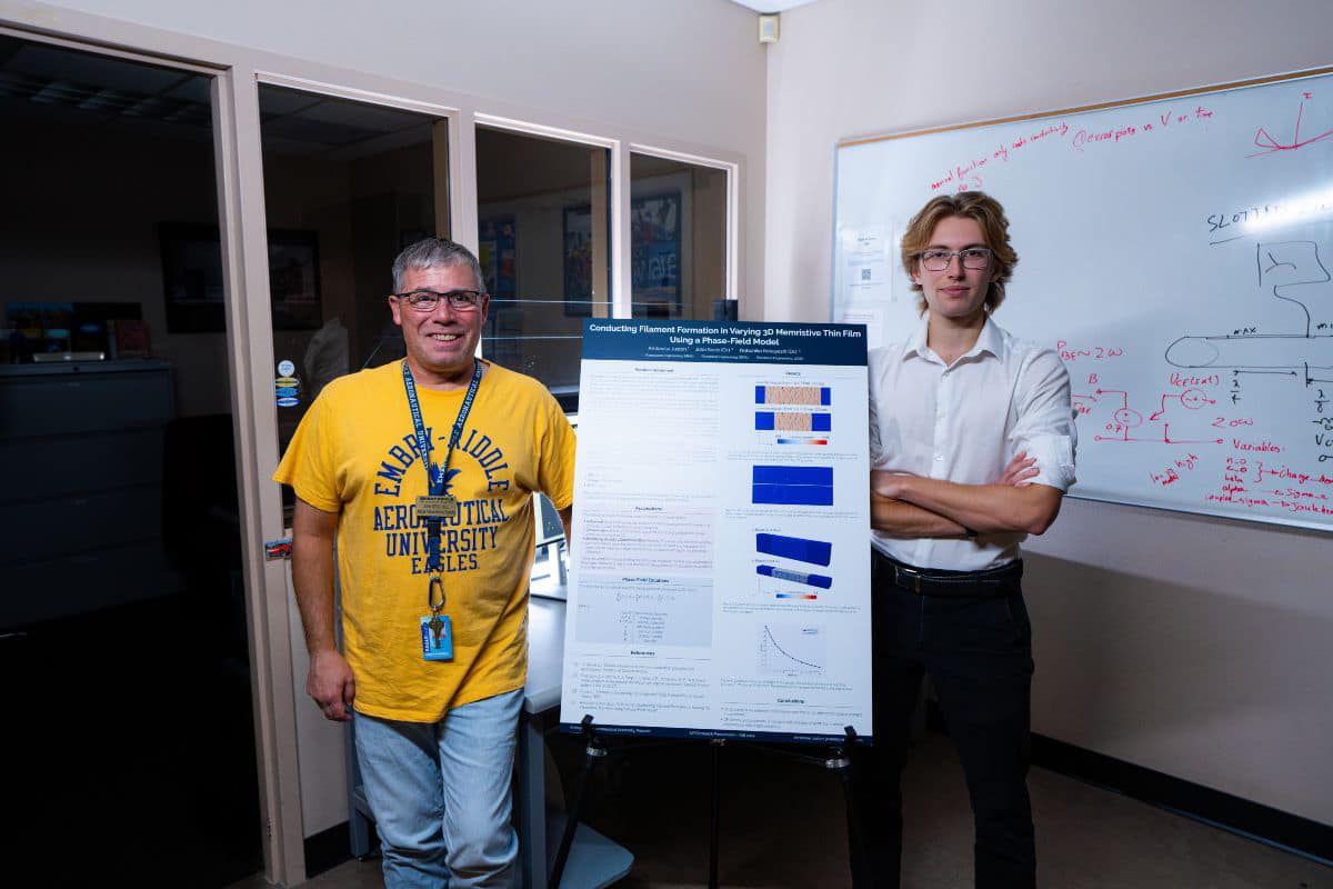 Aerospace Engineering undergraduate Ambroise Juston and Dr. John F. Sevic, professor of electrical engineering, show off a poster summarizing their recent research on memristors.