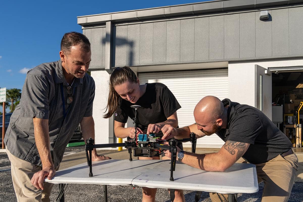 Dr. Marc Compere and undergraduate engineering students Leah Smith and Erik Libergall work to integrate senors onto a drone.