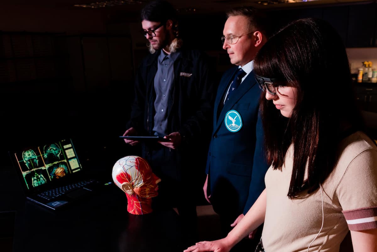 Professor and two students study models of the human head