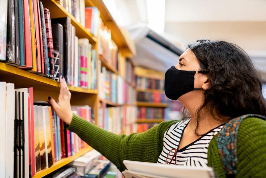 Woman wearing a mask looking at library books
