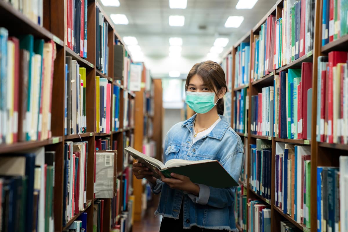 Woman in a library wearing a mask