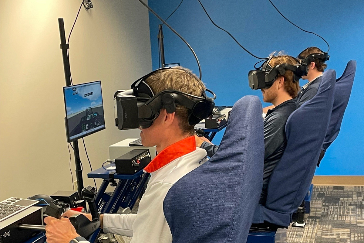 Professional race car drivers (from left to right) Mark Wilkins, Mason Filippi and Harry Gottsacker test their aviation skills using simulators at Embry-Riddle Aeronautical University.