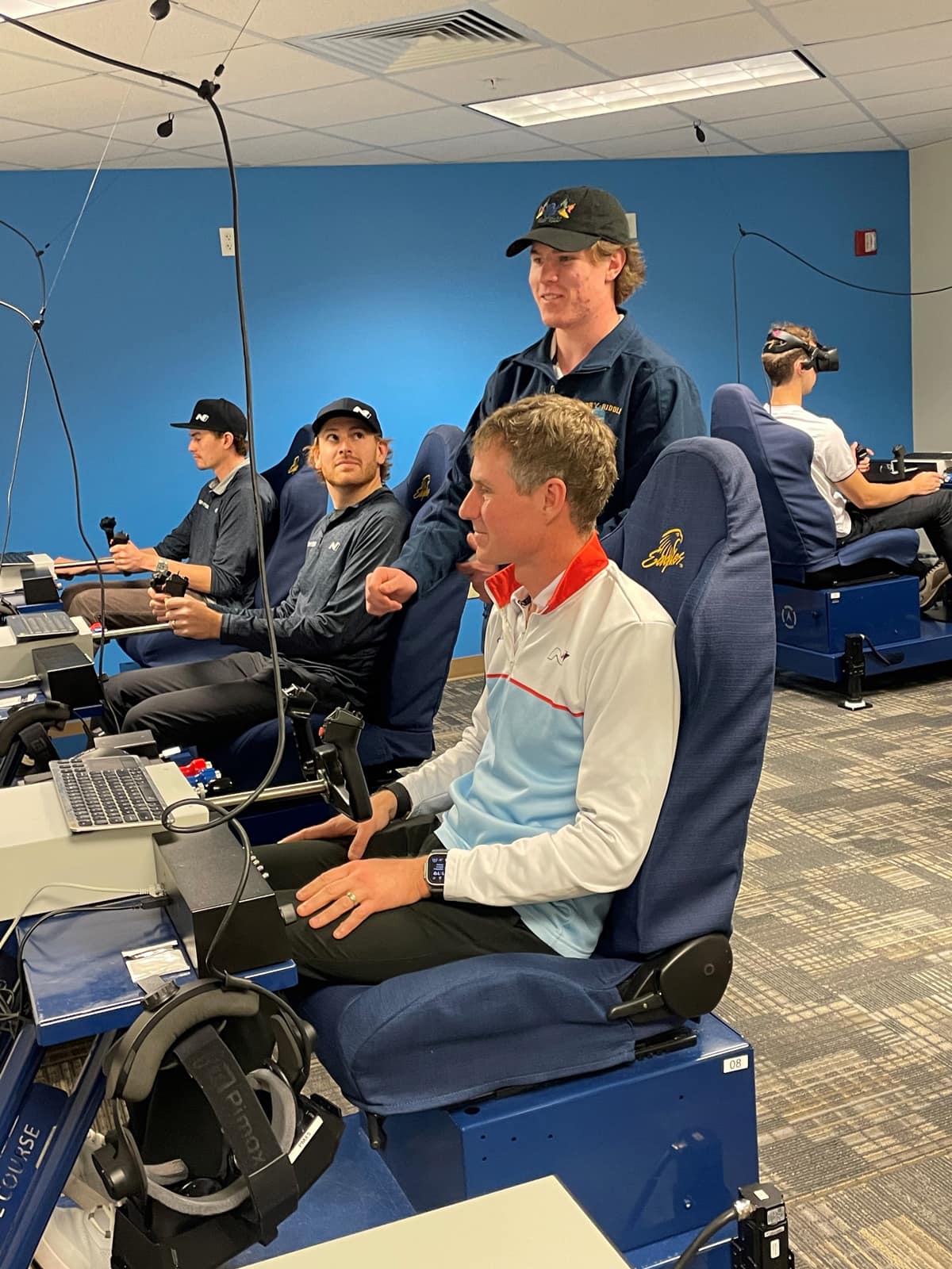 Embry-Riddle student employee Ryan Obert explains the Canyon Time Trail flight simulation to Wilkins, Filippi and Gottsacker, 