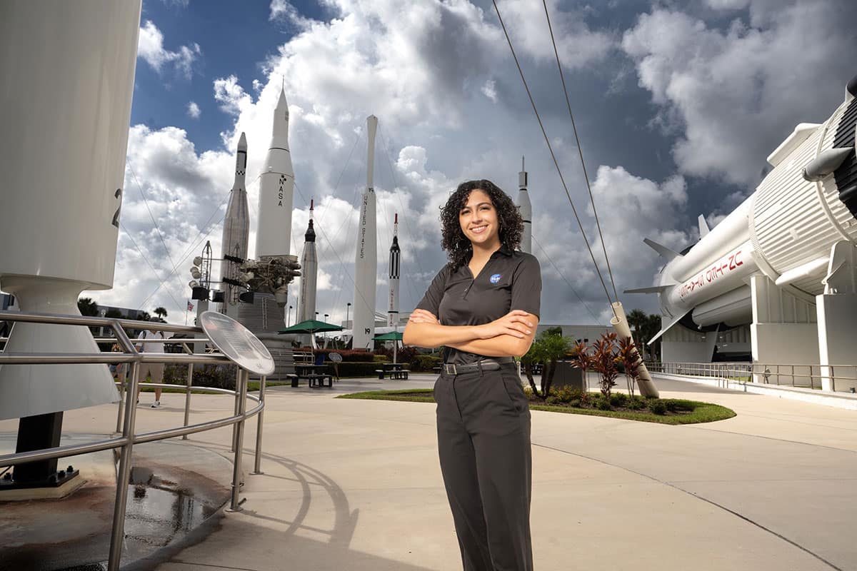 Aviation Week 20 Twenties honoree Liz Bosch stands between a Delta II (left) and a Saturn 1B in the Rocket Garden at Kennedy Space Center