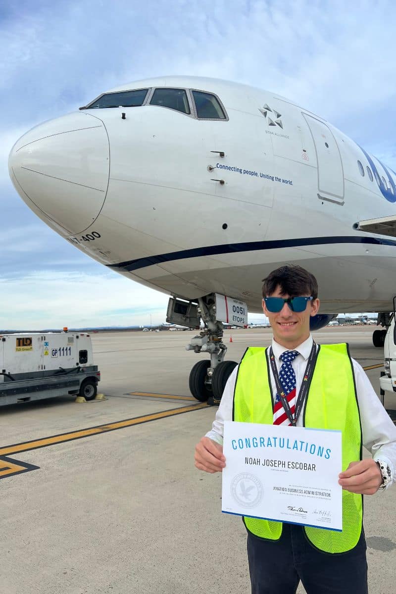 Escobar stands on the ramp in front of a United 767 while holding his acceptance letter to Embry-Riddle Aeronautical University’s Prescott Campus, where he is studying Aviation Business Administration. 