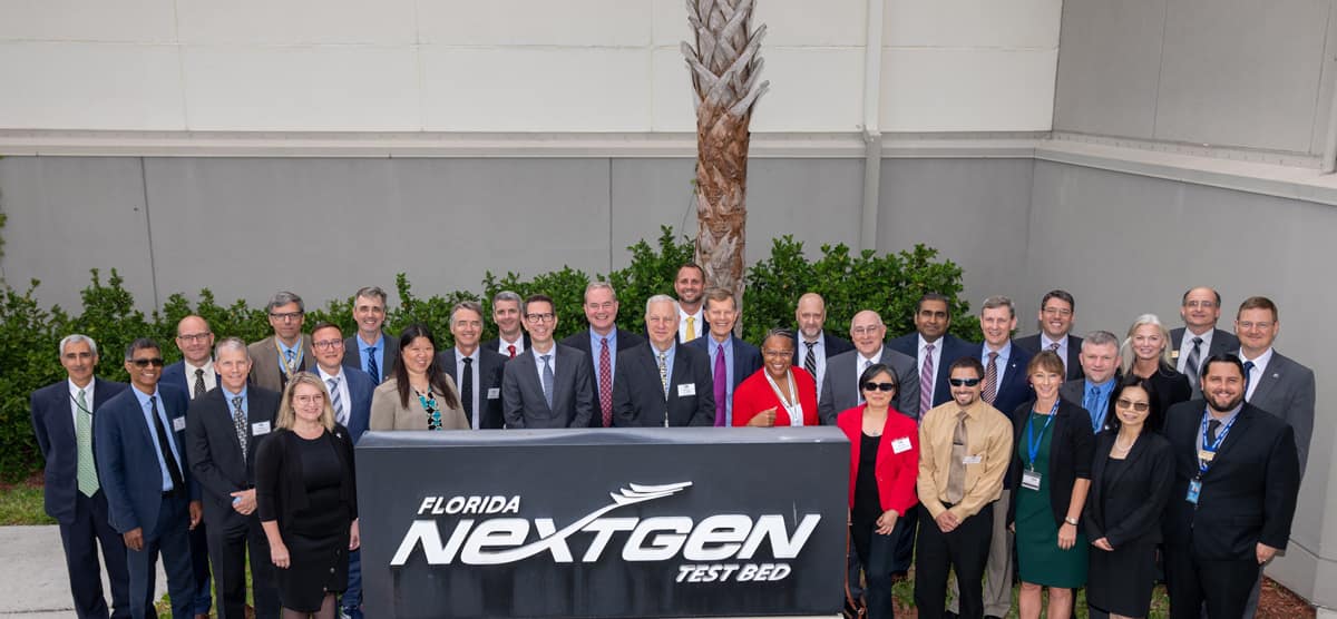 A group of VIP attendees pose together at the inaugural Multi-Regional Trajectory Based Operations (MR TBO) demonstration flight event.