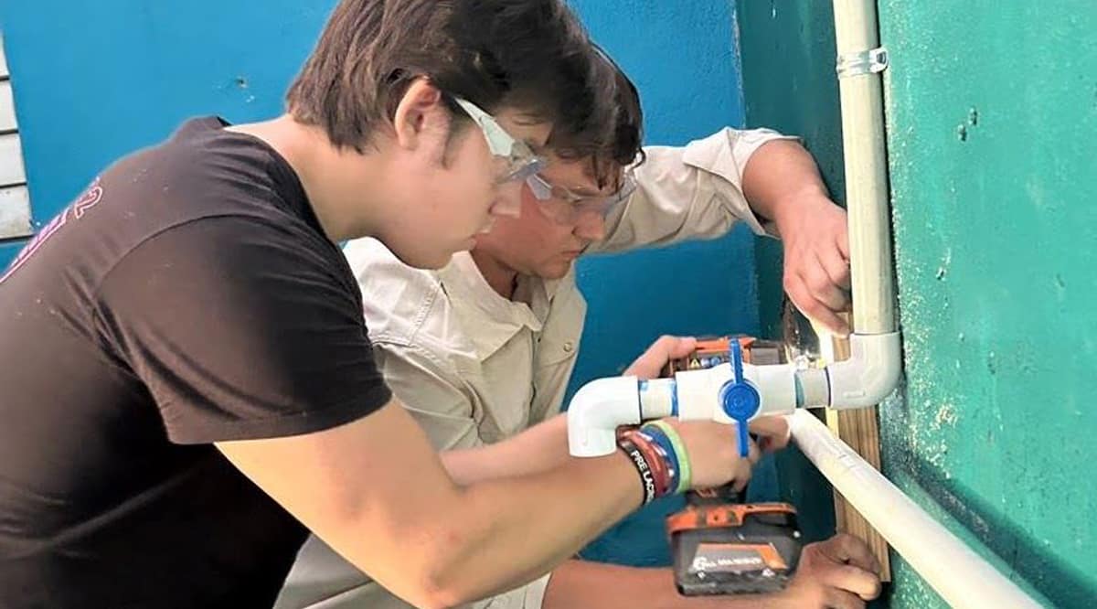 Students Avery Stivers and Tyler Ludwig work on installing the Pure Water Project’s solar-powered water purification system at a community center in the Dominican Republic.