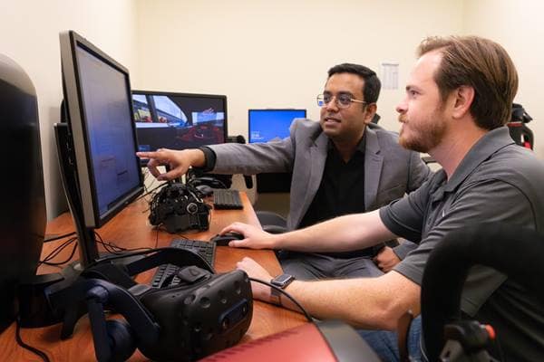 Dr. Subhradeep Roy (left) and Ph.D. student Daniel Lane (right) will utilize VR equipment and an electroencephalogram cap with the driving simulator to better understand automobile driving behavior.