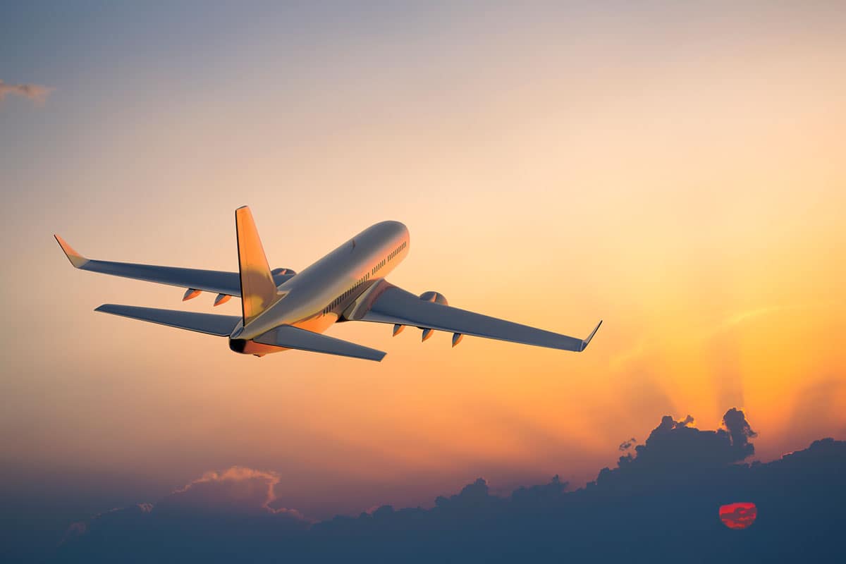 An airplane flying with a sunset in the background