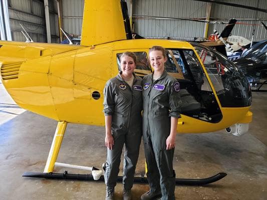 High school students Taylor Shaffer and Chantel Chenard stand by a helicopter