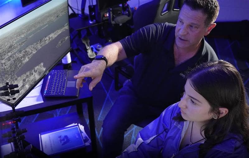 High school student being mentored in a flight simulator by a college instructor