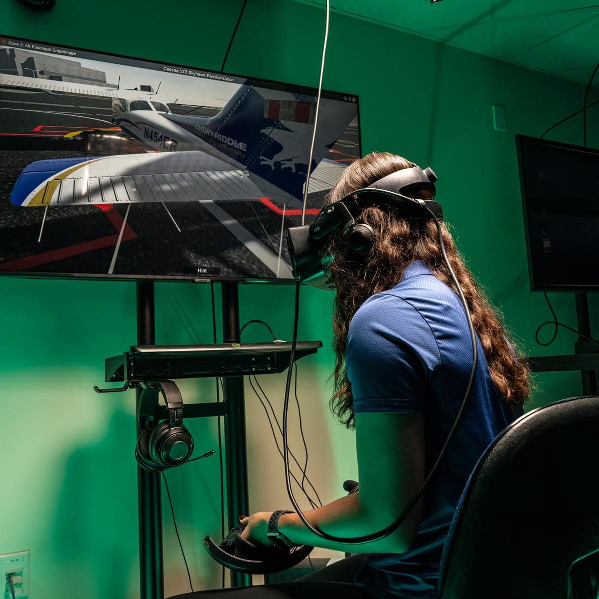 Student in headset with screen showing three-dimensional model of Cessna 172