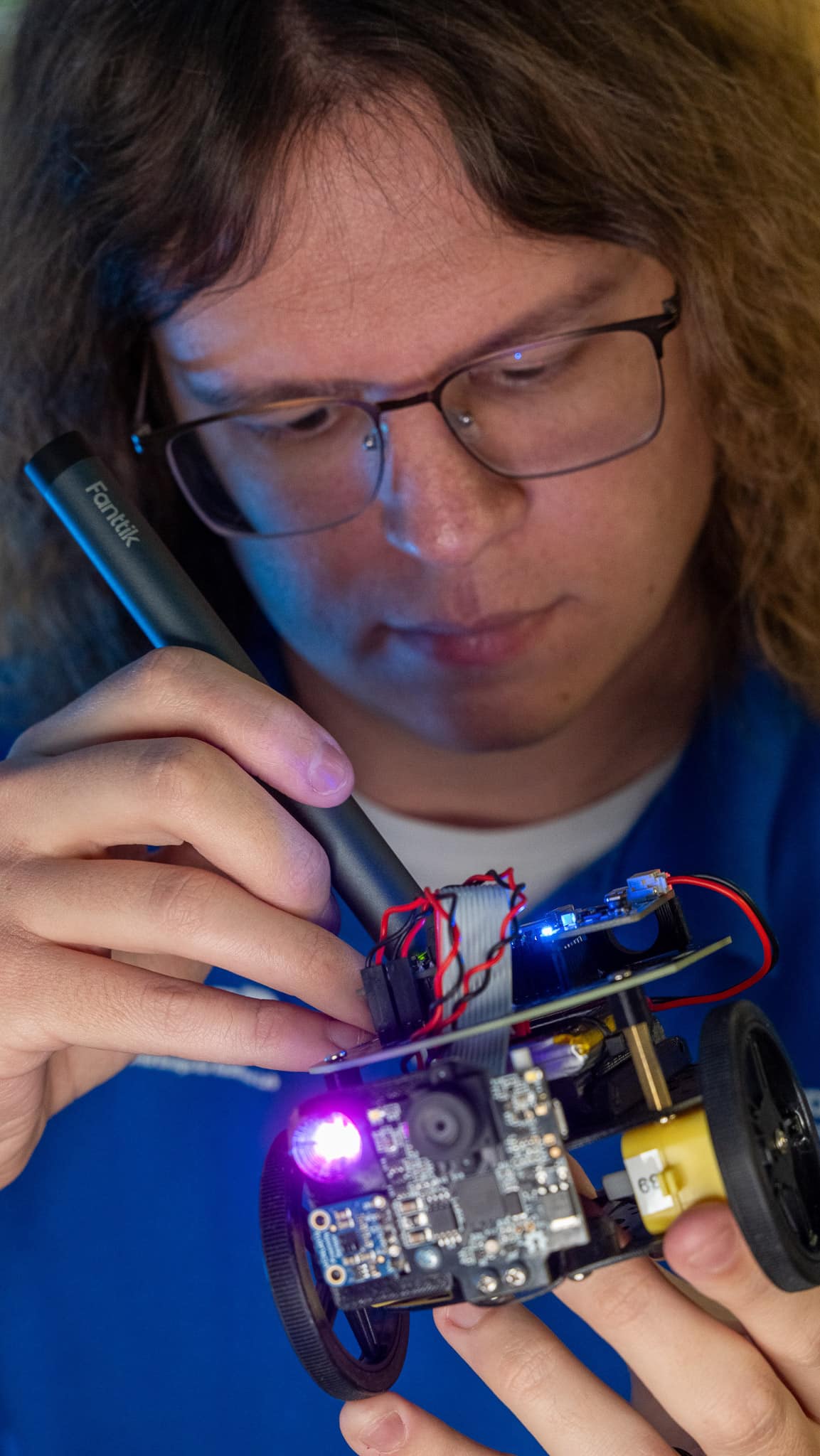 Embry-Riddle student James Hand points a light at a small robot