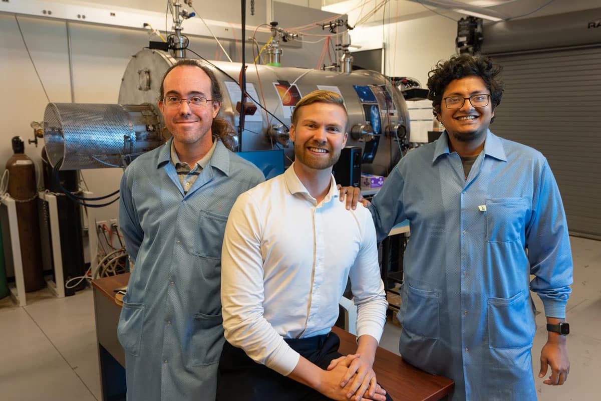 Researchers Robert Clayton, Björn Bergsson and Shantanab Debchoudhury stand in front of the plasma chamber