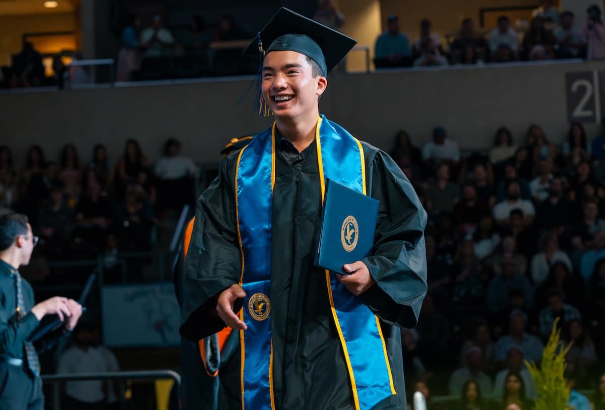 Man walks across stage at a commencement ceremony