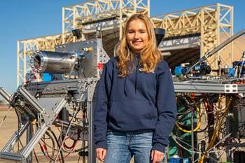 AJ Giza, the project lead for Triton, stands near the rocket engine before its hot fire test