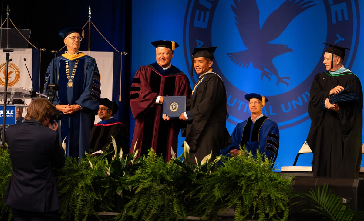 Worldwide Campus Chancellor Dr. John Watret shakes the hand of a graduate