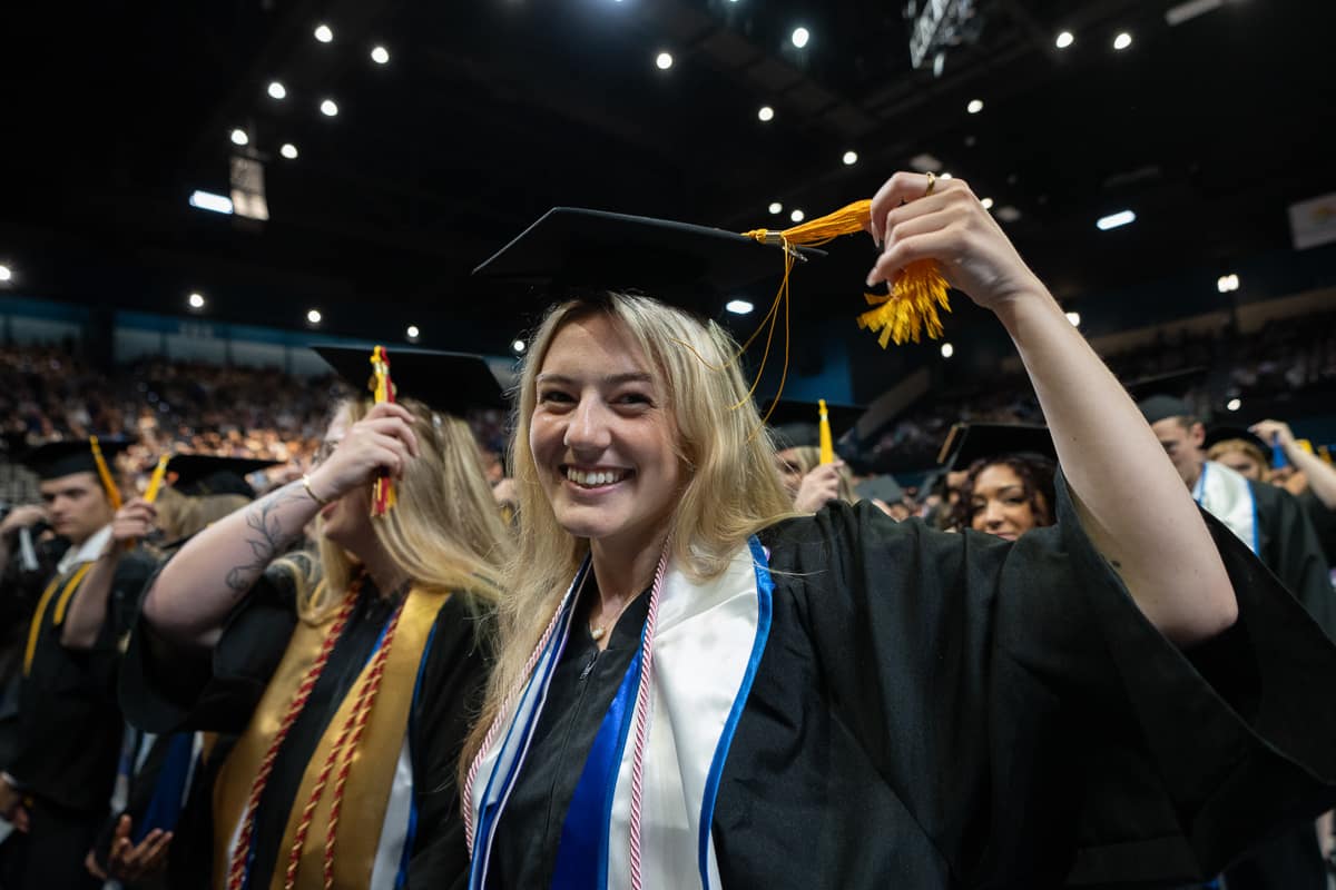 Woman in cap and gown holds tassle