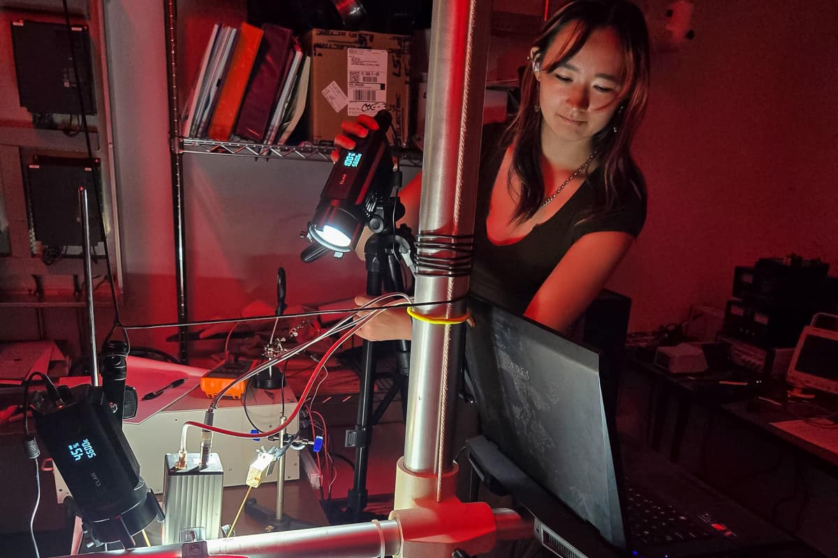 Woman stands in front of light and wires in a lab setting