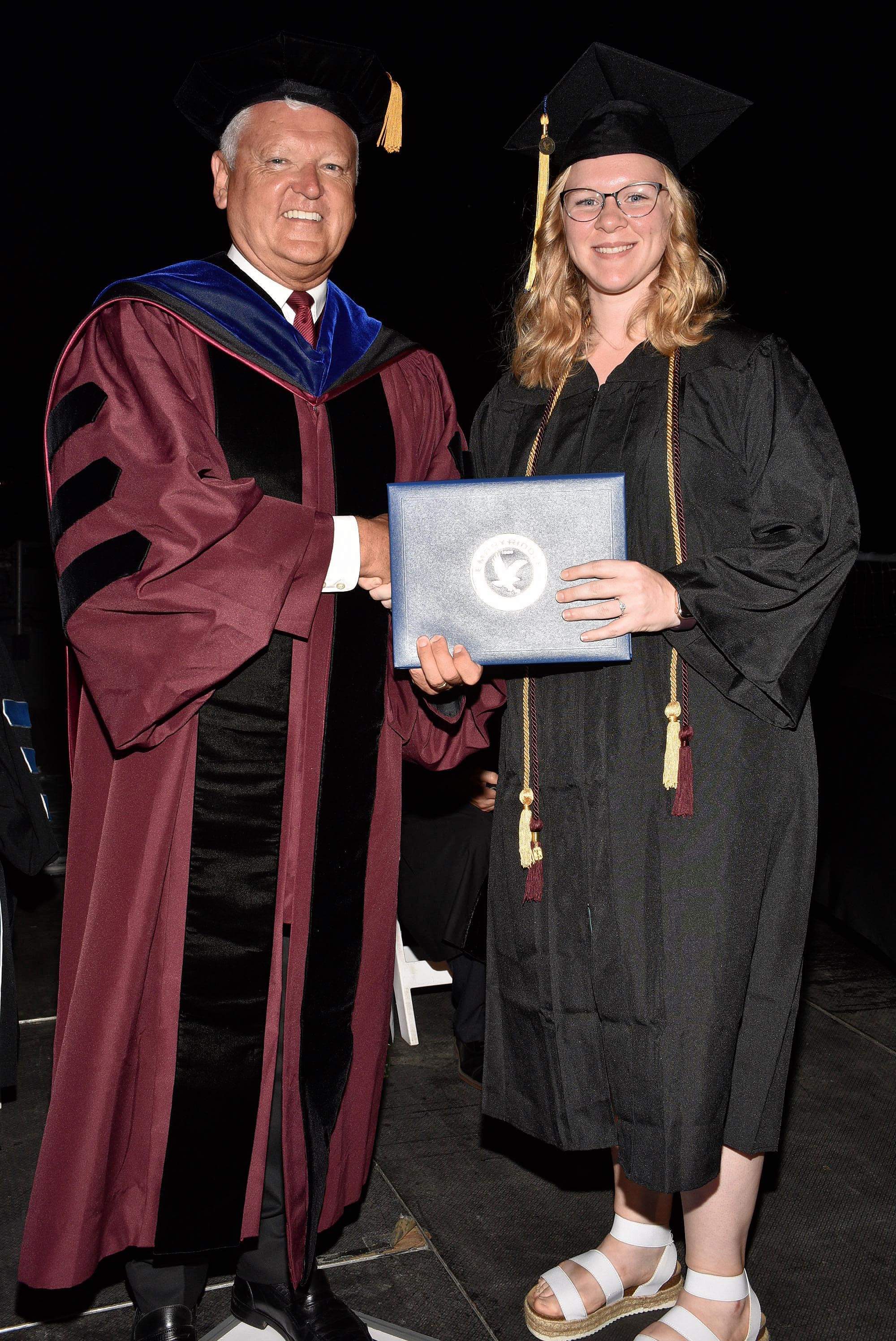Ayesha Ward proudly accepts her A.S. in Aviation Business Administration from Worldwide Chancellor John R. Watret.